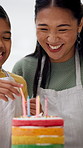 Candles, laugh and mom with child with cake, dessert and sweet treats for celebration in home. Family, happy and mother with girl for birthday, bonding and help for decoration, learning and baking