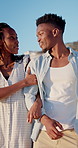 Hug, black couple and walk on holiday at beach for honeymoon trip, conversation and bonding. Love, happy people or embrace at seaside for romantic stroll, healthy relationship or anniversary vacation