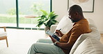 Man, writing and remote work in home with tablet, review proposal and campaign for digital marketing. Mature, black person and freelancer on sofa with tech, stylus or online checklist for advertising