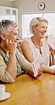 Laugh, mature women and cards in home for friendly competition, social bonding or weekend fun. Relax, happy friends and playing game at table with funny conversation, connection and holiday gathering