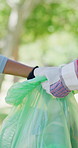 Volunteer, hands and plastic bag in park with garbage collection, recycling project and charity team. Bokeh, people clean outdoor and gloves for rubbish, collaboration and sustainable NGO initiative.