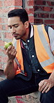 Builder, man and eating at construction site with break, fruit and thinking for building renovation. Person, apple snack and worker rest outdoor with industrial job, vision or contemplation for work.