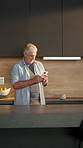 Relax, phone and senior man in kitchen at house with texting, networking or email on mobile app. Happy, technology and elderly male person with cellphone for connectivity or communication in home.