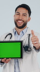 Face, tablet and happy doctor with green screen, thumbs up and healthcare marketing in studio. Tech, man or medical worker with mockup space, like sign or point for telehealth ads on white background