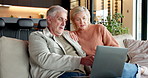 Elderly, couple and sofa with laptop for online browsing, network or discussion together in home. Senior, man and woman planning retirement with computer for holiday, weekend or break in house