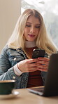 Chat, online and woman with phone in cafe, freelance and article research with laptop and networking. Creative, writer and happy person with mobile, texting and reading message on web in coffee shop