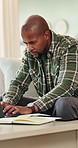 Black man, laptop and typing with remote work from home on sofa, notes and proposal in living room. African person, virtual assistant and computer in lounge with review, feedback and insight at house