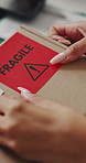 Person, hands and box with fragile sticker for logistics, small business distribution or delivery. Top view, distributor or supplier with caution label on courier package or parcel for freight safety