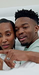 Couple, scroll and smile in bedroom, decision and movie selection with partner or discussion in home. Black people, talking and film choice with spouse on website, point and watching videos in house