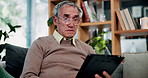 Glasses, tablet and typing with old man on sofa in living room of home for reading or scrolling. App, eyewear and research with surprised senior at apartment for internet browsing or retirement