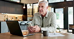 Thinking, phone and laptop with old man in kitchen for social media, ebook subscription and relax. Online taxes, problem solving and mature person in home, tech for communication and finance planning