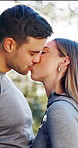 Athlete, couple and kiss in nature with love, affection and partner support for morning fitness. Bokeh, smile and people at park with romance, connection and bonding together for healthy relationship