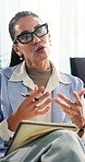 Woman, therapy and psychologist with notebook, talk and evaluation in counseling office for help. Psychology, mature person and speaking with notes for advice, support or mental health assessment