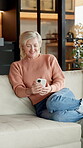 Laughing, phone and relax with old woman on sofa in home living room for social media browsing. App, text message and typing with funny senior person in apartment for break, retirement or wellness
