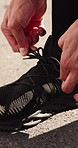 Fitness, hands and fasten shoes on road outdoor to start training, wellness and practice preparation. Sneakers, person and runner tying shoelace for getting ready, sports safety and health on street