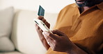 Man, hands and phone with credit card in home for online shopping, payment or banking app on sofa. Male person, shopper or smartphone with debit for mobile purchase, ecommerce or wireless transaction