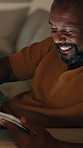 Night, man and reading in living room with tablet, laugh and ebook with funny joke on weekend break. Late, happy and mature black person in home with digital tech, browsing or humor for online story.