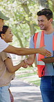 Clipboard, volunteers and handshake with welcome at park for outreach project, signup or vests. Checklist, people and coordinator with shaking hands outdoor for community service, greeting or charity