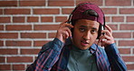 Headphones, man and face of student by brick wall for listening to music, playlist or radio at college. Happy, audio tech and portrait of male person with streaming album online at university campus.
