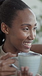Smile, black woman and relax in home with coffee, start day and calm morning in living room. Female person, people and laugh at house with beverage, funny discussion and comfortable for weekend break
