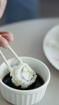 Hands, person and eating sushi with sauce, culinary and seafood cuisine for lunch. Closeup, customer and Japanese dish with chopsticks, gourmet appetizer and raw fish flavor for authentic delicacy