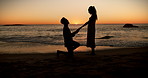 Sunset, proposal and couple on beach with love, question or surprise romantic gesture in nature. Engagement, holding hands and silhouette of people at sea with support for marriage and commitment