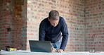 Laptop, man and writing on construction site for blueprint correction, drawing update or renovation. Tech, mature architect and notes on floor plan for building design, layout change and compliance
