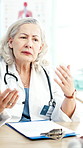 Clipboard, discussion and doctor in office at hospital with research for medical diagnosis or treatment. Patient records, woman and mature healthcare worker with conversation in checkup at clinic.