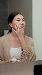 Mirror, skincare and asian woman with face cream in bathroom, korean beauty product and grooming. Reflection, apply and person with niacinamide moisturizer for glass skin aesthetic, smile and home