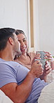 Couple, talk and drinking coffee in bed with laugh, bonding together or funny gossip on weekend break. Morning, happy people dating and relax in home with warm tea, humor or loyalty for relationship.