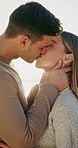 Love, travel and couple with kiss on beach for romance, date and anniversary vacation or bonding together. Sunset, smile and happy people with affection for weekend holiday, loyalty and support