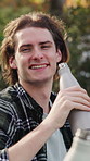 Man, happy and toast with drink for camping, bonding and relax in nature environment to celebrate. People, bottle and cheers with beverage on holiday, vacation or trip in woods with joke and laugh