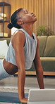Yoga, girl and stretching with tablet in house for online class, posture or holistic routine. Yogi, black woman or cobra pose in digital lesson for lumbar flexibility, health subscription or wellness