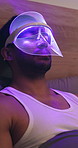 Mask, calm and man with red light therapy on bed for skincare, beauty or facial wellness. Relax, cosmetic and person with face LED treatment for collagen production or glow in bedroom at apartment.