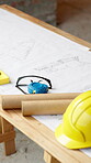 Helmet, floorplan or table at construction site for planning, renovation or property development. Hard hat, blueprint or safety equipment at worksite for compliance, tape measure or civil engineering