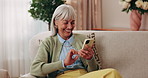 Cellphone, happy and senior woman on sofa in home for texting, notification or social media. Smile, relax and elderly person with phone for reading blog, update or email on mobile app in living room.