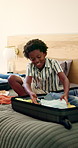 Packing, bedroom and child with clothes in suitcase for travel, vacation and family holiday. Happy, home and African kid with luggage, outfits and prepare for adventure, weekend getaway and trip