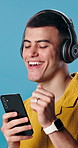 Dance, phone and man with headphones in studio for good mood, positivity and happy on weekend. Rhythm, dancer and person with mobile app for streaming music, playlist and radio on blue background