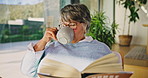 Coffee, home and senior woman reading book with glasses, relax and author research in lounge. Elderly person, literature or fiction for knowledge development with tea and calm retirement in house