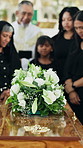 Sad, people and priest at funeral with coffin, condolences and memorial service for deceased. Family, pastor and flowers on casket at church for sermon, final goodbye and burial for farewell ceremony