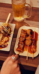 Woman, hands and pointing with chicken skewer in restaurant above for food or cuisine. Top view, female person or poultry sticks with recipe, snack or sauce for kebab, Yakitori or eating in diner