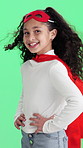 Face, kid and superhero in studio with confidence, smile and pretend with wind on green background. Portrait, cape and happy girl with costume, fantasy cosplay or fearless child role play for justice