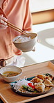 Hands, woman and eating at house with chopsticks, healthy rice and traditional meal for lunch. Female person, bowl and utensils in home for brunch platter, nutrition snack and authentic Asian cuisine