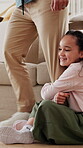 Leg, clinging and dad with child in lounge, playful resistance and connection with parent on weekend. Walking, man and seeking attention from father, happy girl and family attachment on break in home