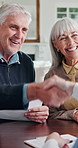 Happy, senior couple and handshake with financial advisor in home, agreement and chat with document. Wealth management, advice and shaking hands with old people, smile or talk with paperwork in house