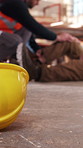 Hard hat, help and construction workers on site with accident, fall or leg fracture on duty. Muscle sprain, men and civil engineers with assistance for torn ligament, knee pain or medical emergency.