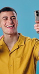 Man, smile and selfie in studio for live streaming, check style or fashion photography. Male person, app and capture photo for profile picture, social media update and laughing on blue background