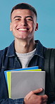 Books, face and man in studio for university, college and smile for learning and studying. Happy, portrait and student with textbooks, backpack or excited for education, knowledge and blue background