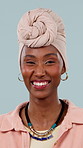 Face, black woman and smile in studio with fashion, casual clothes and stylish turban for culture. Portrait, female person or laugh with headwear, traditional necklace and heritage on blue background