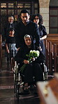 Family, church and woman in a wheelchair for funeral with flowers for memorial, widow or service. Group, arrive or senior person with disability in chapel for christian religion, mourning or sad